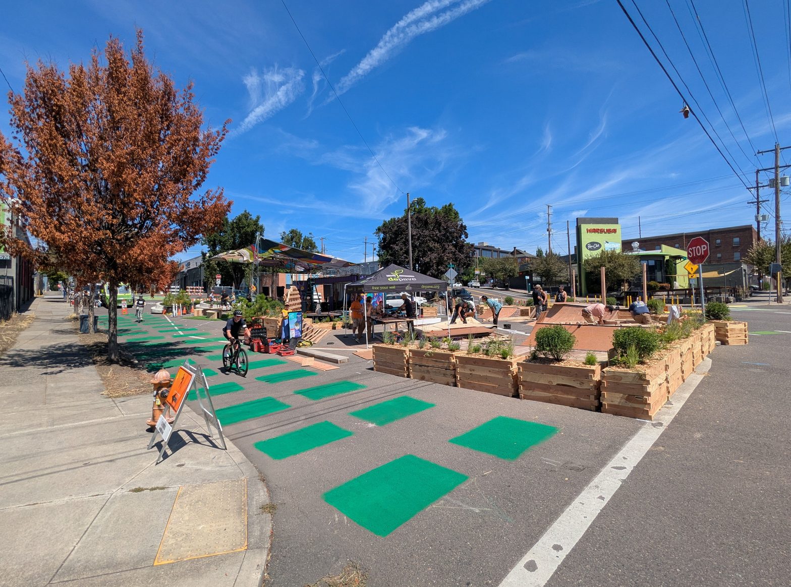 The pop-up plaza at SE 7th and Sandy with painted green surface, planters, and people crossing